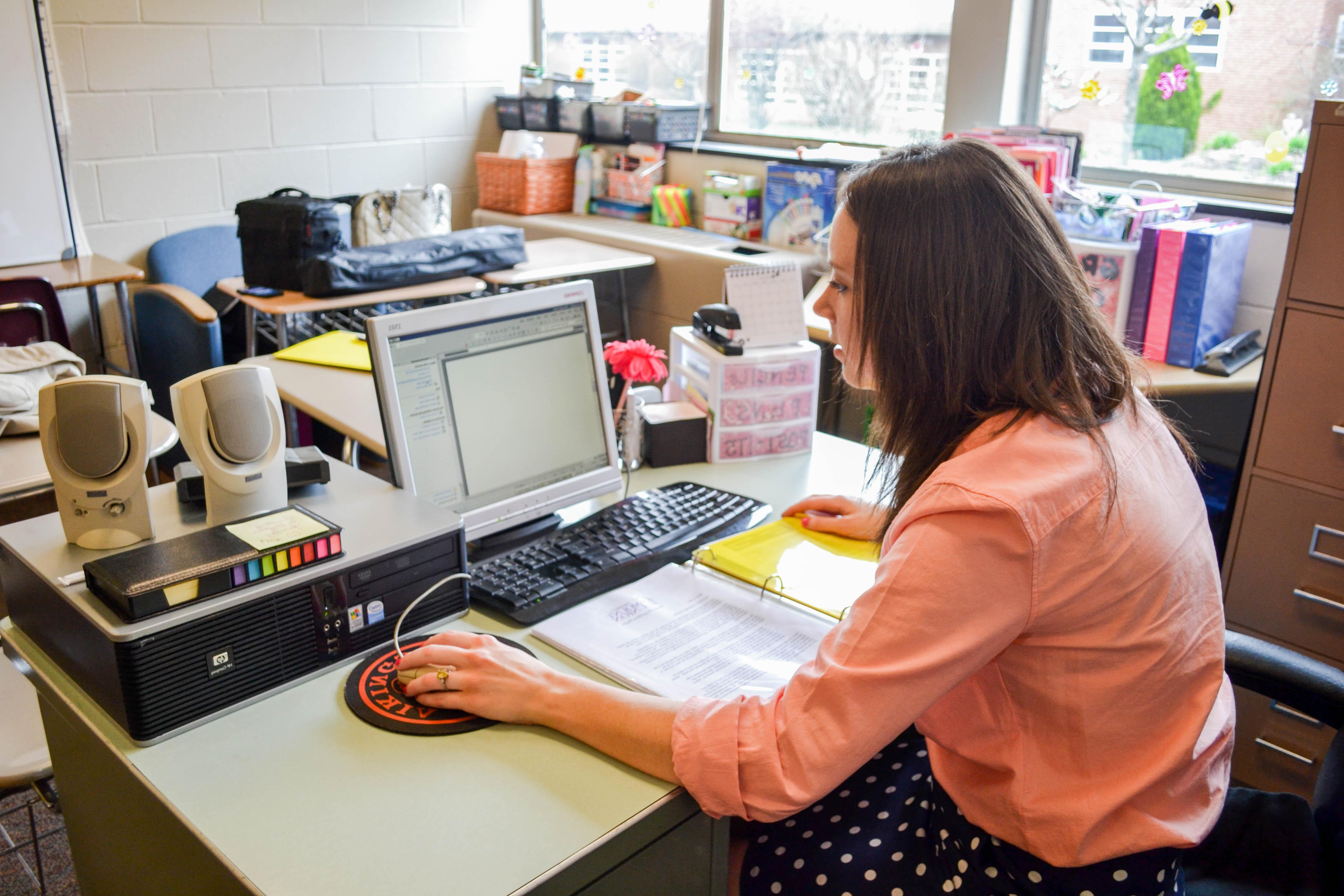 teacher working in classroom on computer